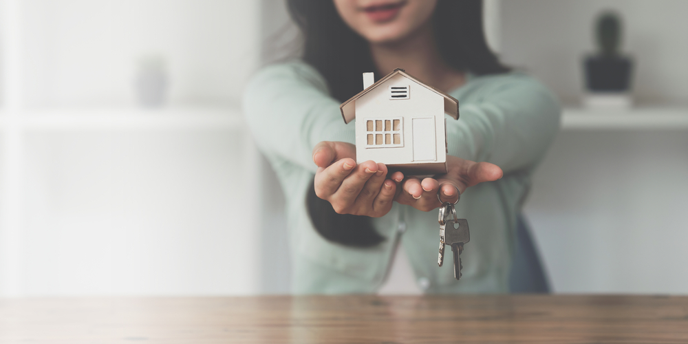 close up business woman or real estate agent giving house key after signing agreement for buying house. bank manager and real estate concept.
