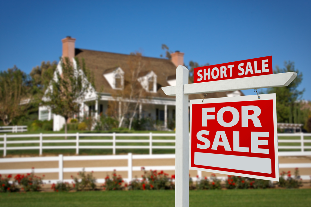 short sale home for sale real estate sign in front of new house.